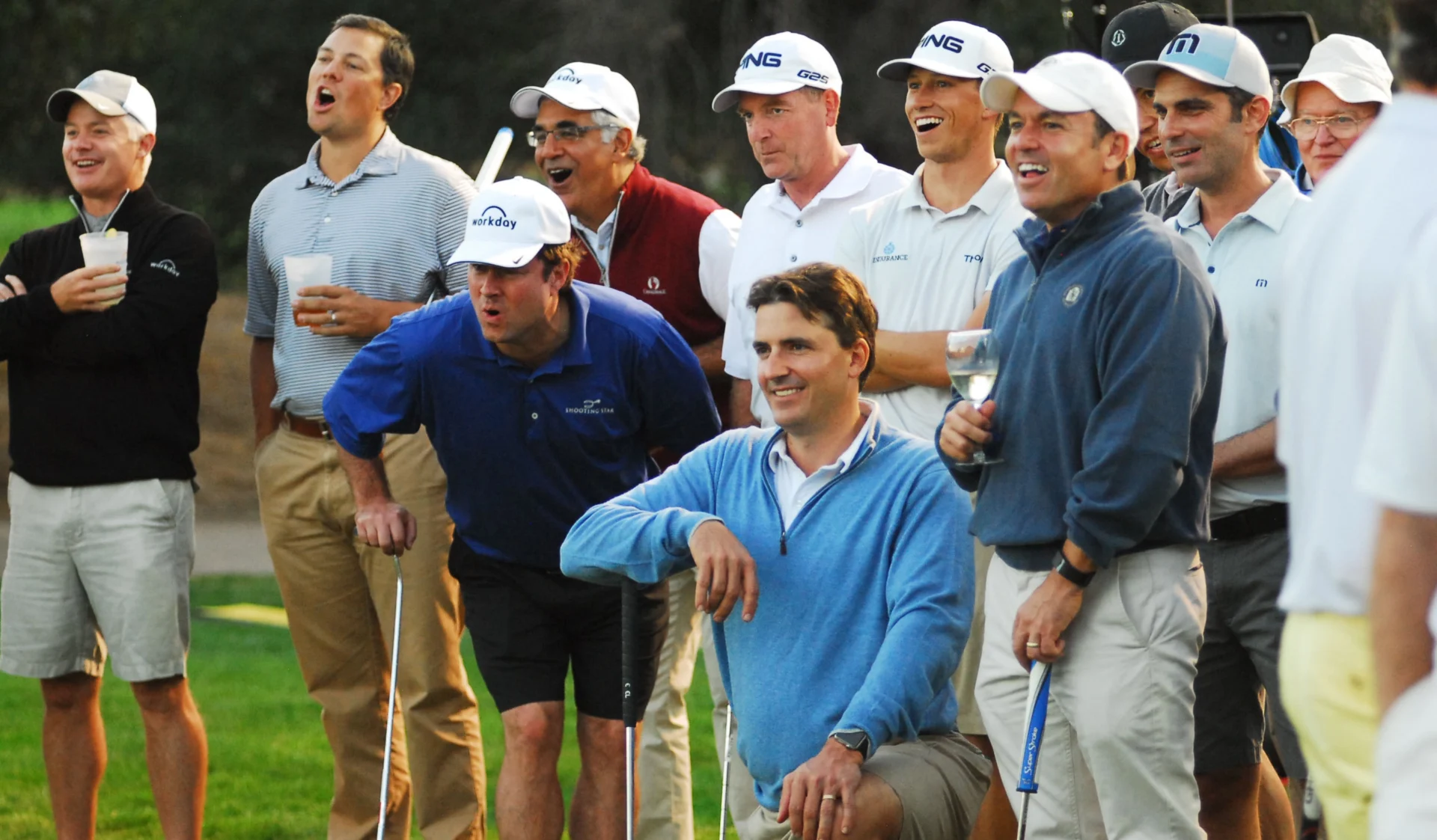 A group of men posing on a golf course, dressed in casual golf attire.