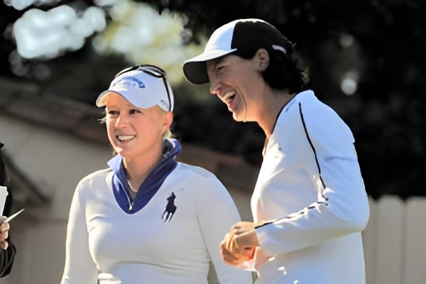Two women in sports attire smiling outdoors.