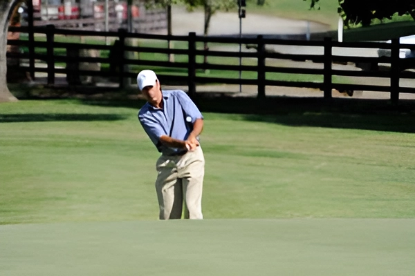 A golfer swings on a green golf course.